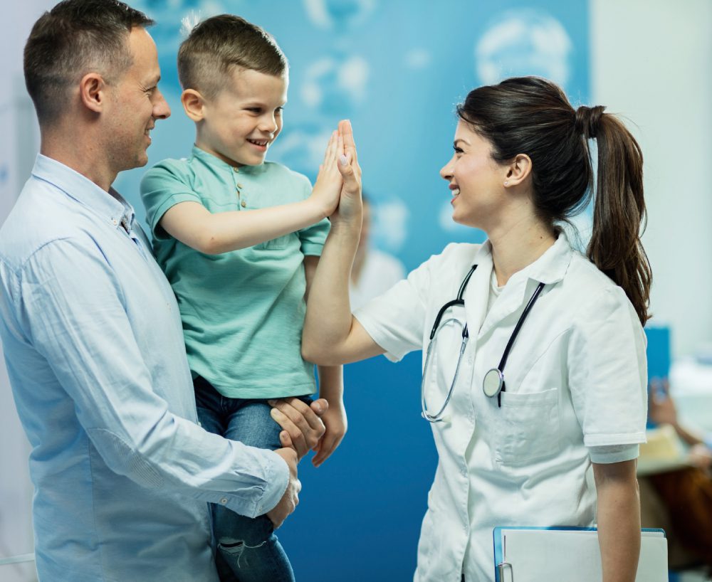 happy female doctor giving high fie to a little boy who came with father at hospital