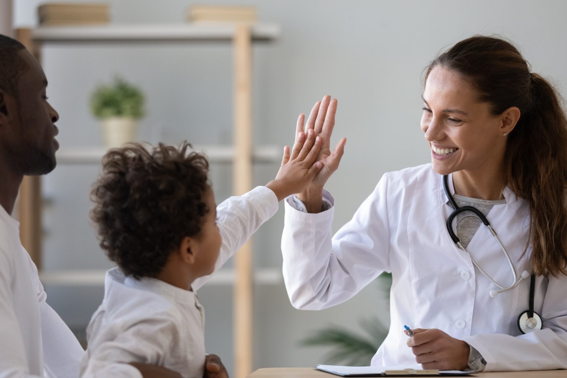 happy female doctor giving high fie to a little boy who came with father at hospital